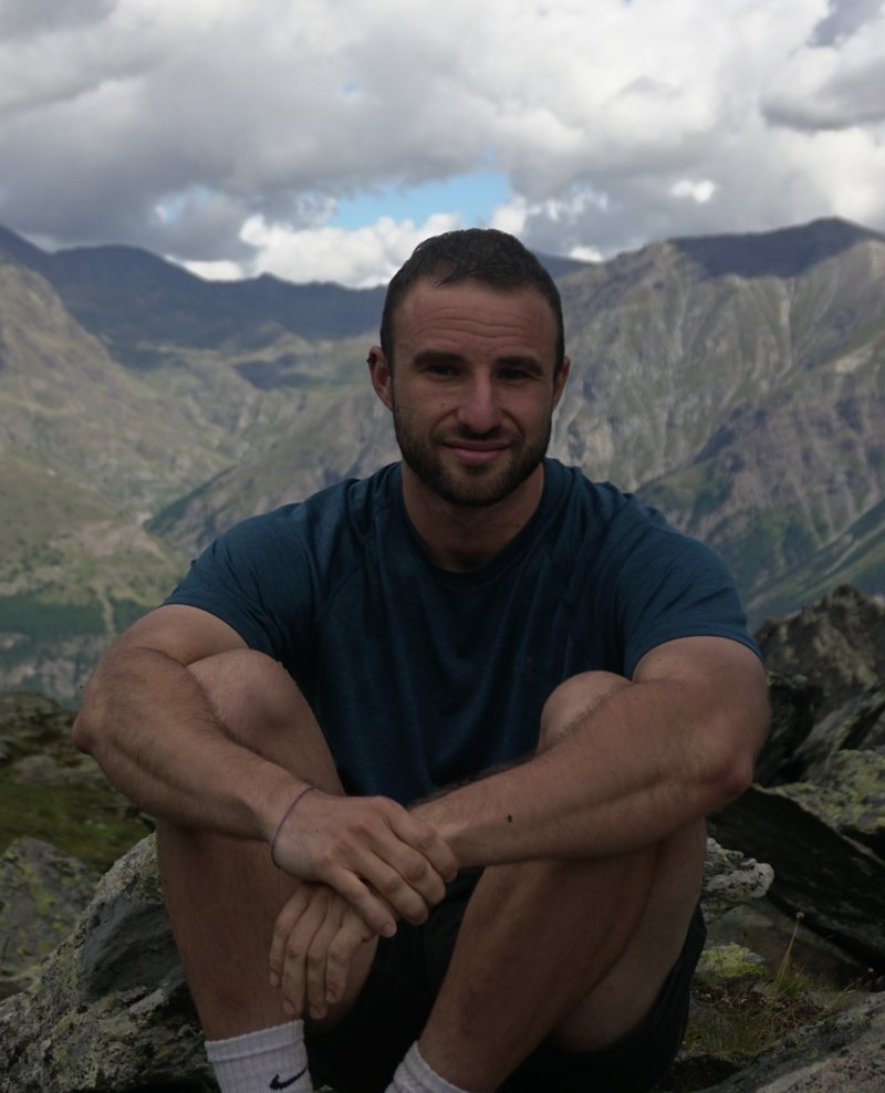 Pablo G. Peña sitting on rocks in the mountains